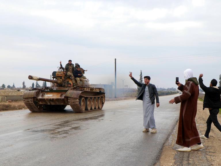 Menschen jubeln bei Rakka einem Panzer der Armee zu.