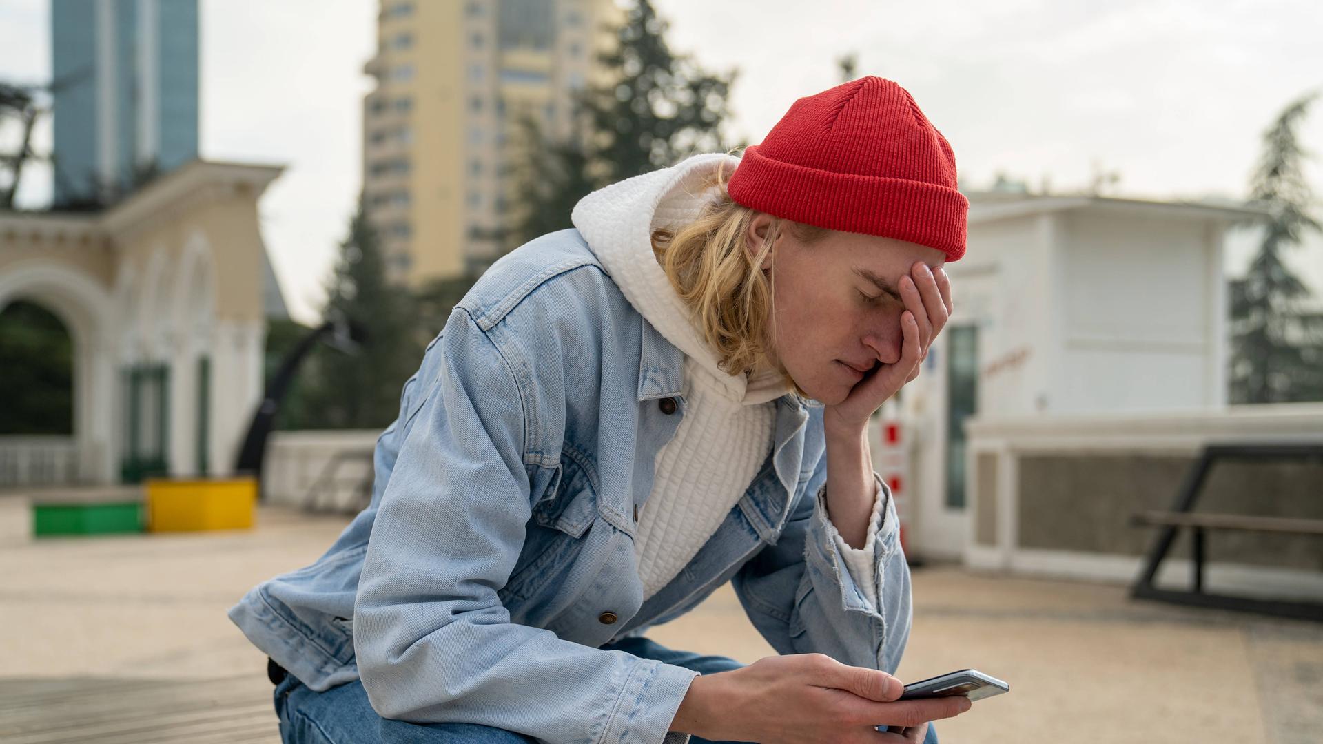 Ein junger Typ schaut auf sein Smartphone und hält sich die hand vors Gesicht. Ein junger Typ schaut auf sein Smartphone und hält sich die hand vors Gesicht.