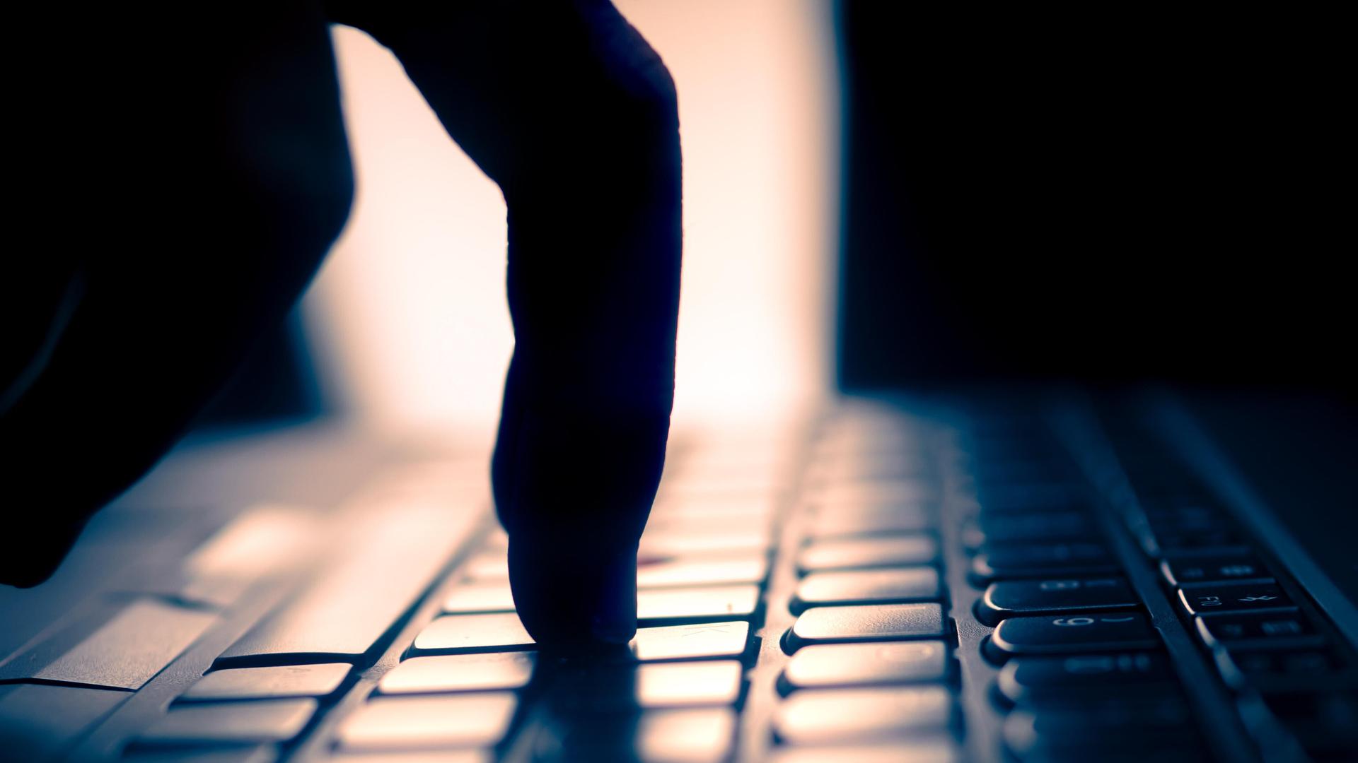 Finger tippt auf Tastatur, dunkle Umgebung und Gegenlicht Finger tippt auf Tastatur, dunkle Umgebung und Gegenlicht