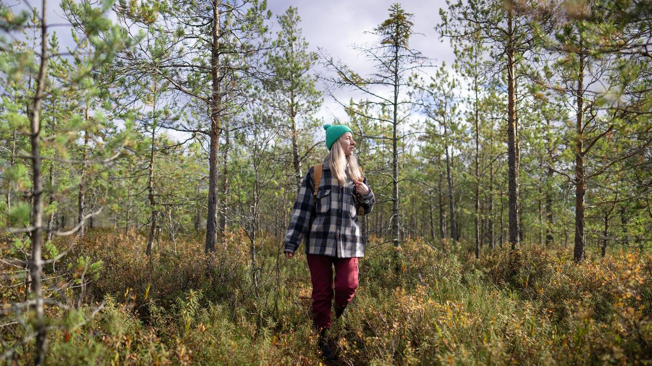 Eine Frau läuft in Wanderkleidung durch einen Wald.
