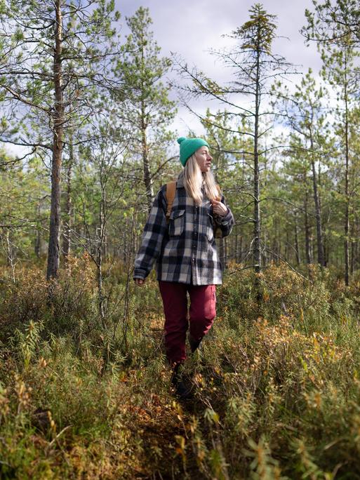 Eine Frau läuft in Wanderkleidung durch einen Wald. Eine Frau läuft in Wanderkleidung durch einen Wald.