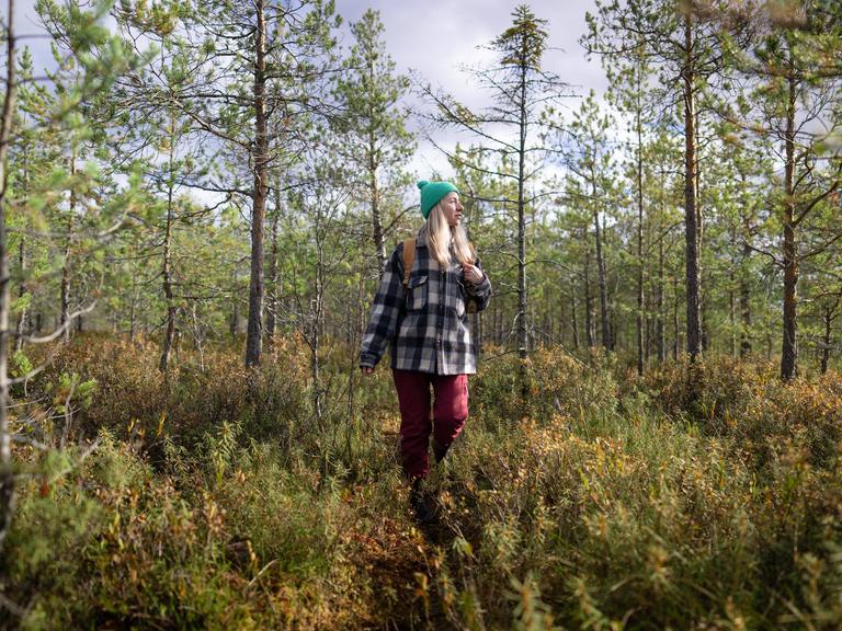 Eine Frau läuft in Wanderkleidung durch einen Wald. Eine Frau läuft in Wanderkleidung durch einen Wald.