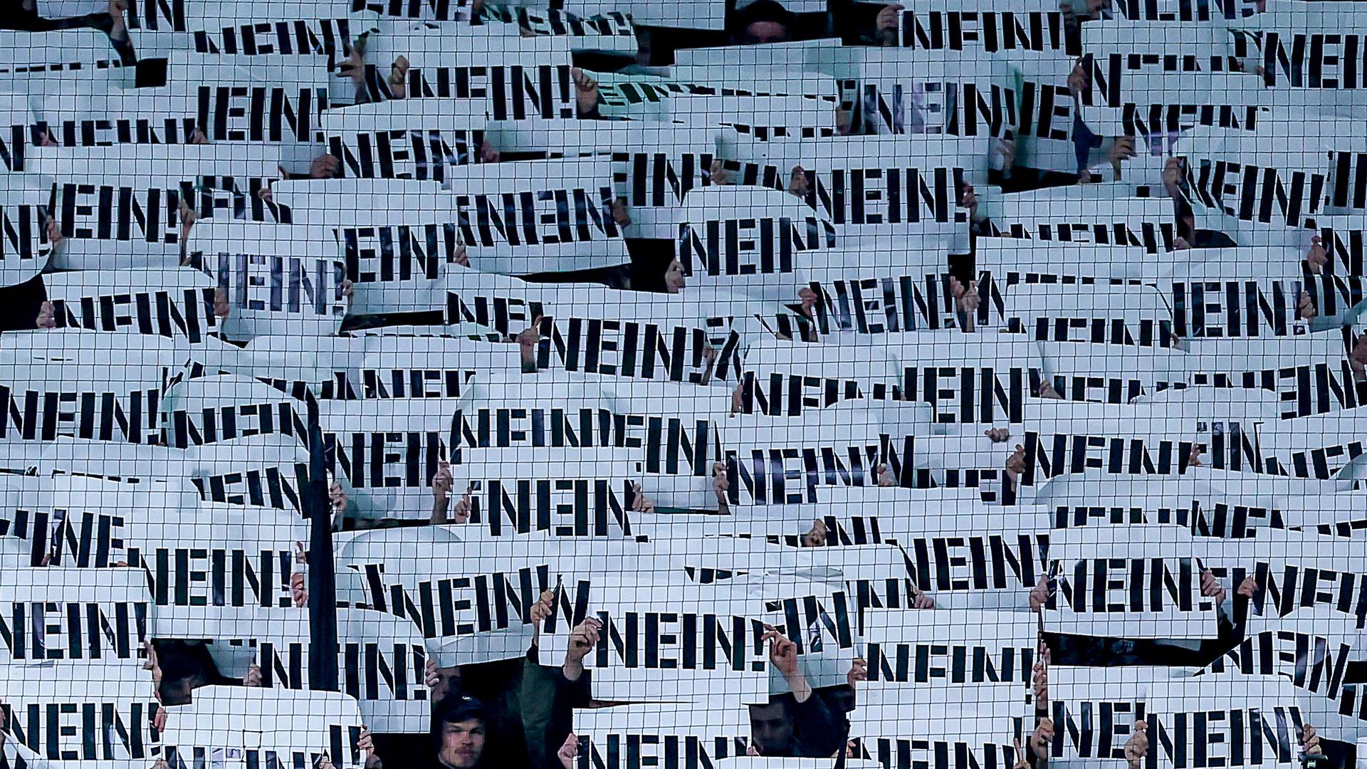 Fußballfans halten Schilder als Protest gegen die Pläne des Bundesinnenministers mit der Aufschrift „NEIN“ vor ihre Gesichter (Borussia-Park Mönchengladbach, 28.11.2025)
