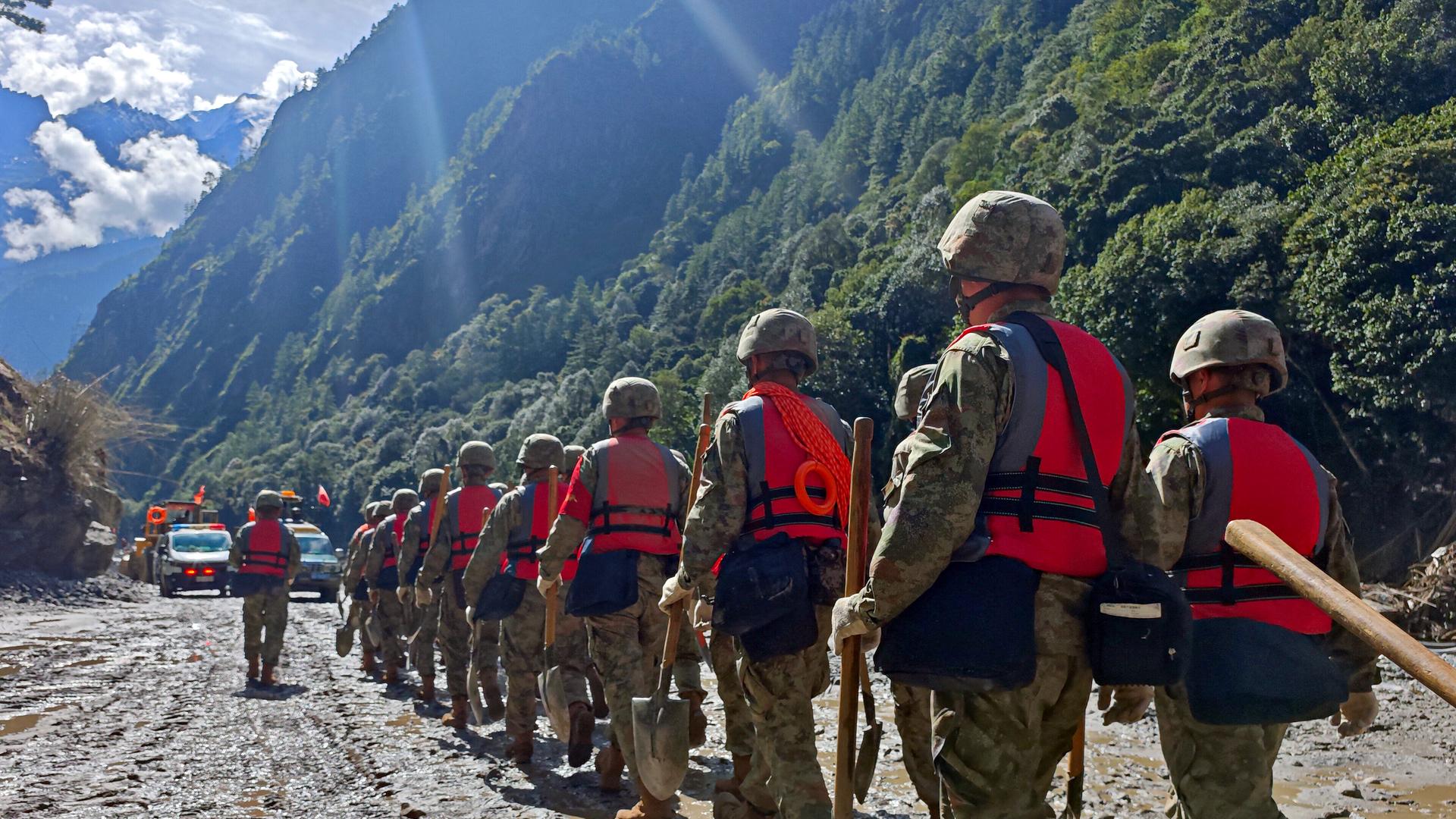 Soldaten der chinesischen Volksbefreiungsarmee laufen durch ein Tal, der Boden ist mit Schlamm überzogen. Es ist eine Rettungsaktion nach der Sturzflut, die auch Tibet getroffen hat. Soldaten der chinesischen Volksbefreiungsarmee laufen durch ein Tal, der Boden ist mit Schlamm überzogen. Es ist eine Rettungsaktion nach der Sturzflut, die auch Tibet getroffen hat.