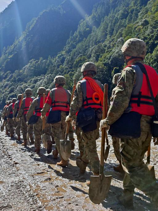 Soldaten der chinesischen Volksbefreiungsarmee laufen durch ein Tal, der Boden ist mit Schlamm überzogen. Es ist eine Rettungsaktion nach der Sturzflut, die auch Tibet getroffen hat. Soldaten der chinesischen Volksbefreiungsarmee laufen durch ein Tal, der Boden ist mit Schlamm überzogen. Es ist eine Rettungsaktion nach der Sturzflut, die auch Tibet getroffen hat.