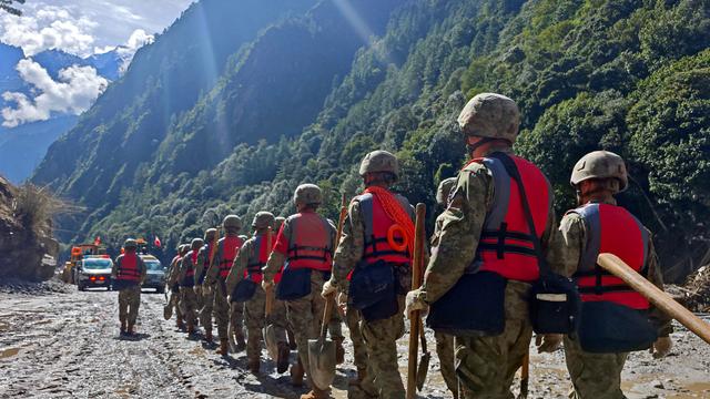 Soldaten der chinesischen Volksbefreiungsarmee laufen durch ein Tal, der Boden ist mit Schlamm überzogen. Es ist eine Rettungsaktion nach der Sturzflut, die auch Tibet getroffen hat.