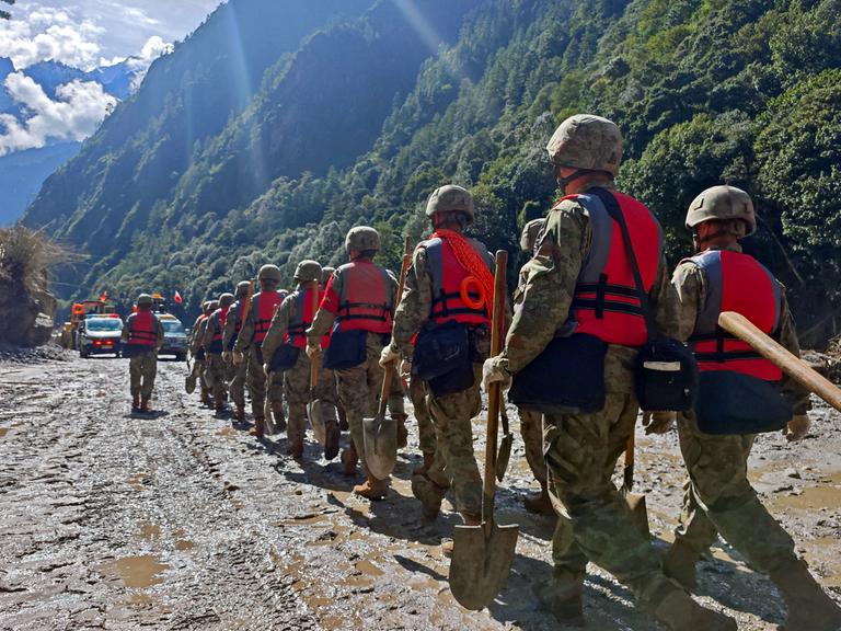Soldaten der chinesischen Volksbefreiungsarmee laufen durch ein Tal, der Boden ist mit Schlamm überzogen. Es ist eine Rettungsaktion nach der Sturzflut, die auch Tibet getroffen hat. Soldaten der chinesischen Volksbefreiungsarmee laufen durch ein Tal, der Boden ist mit Schlamm überzogen. Es ist eine Rettungsaktion nach der Sturzflut, die auch Tibet getroffen hat.