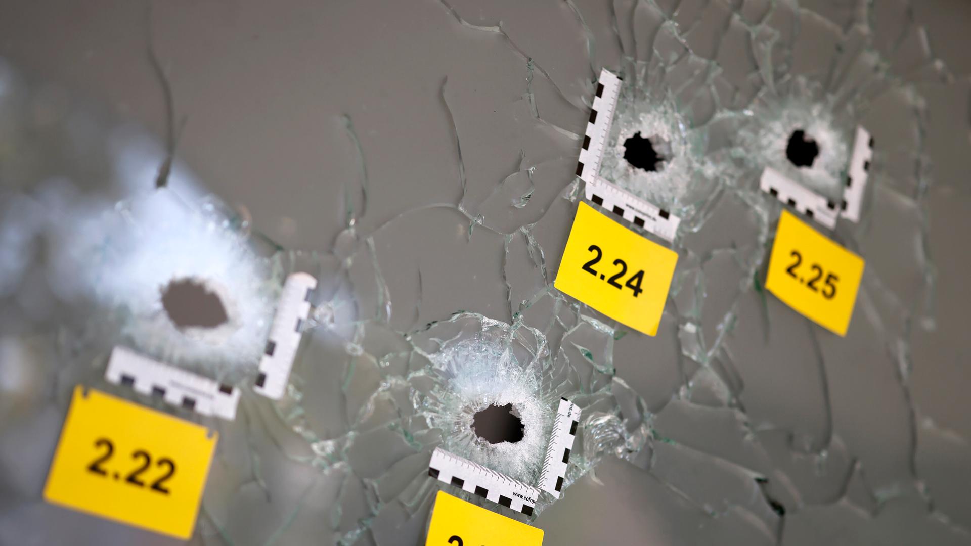 Schusslöcher auf Glasscheibe sind mit polizeilichen Tatortnummern markiert (Köln, 21.09.2024)