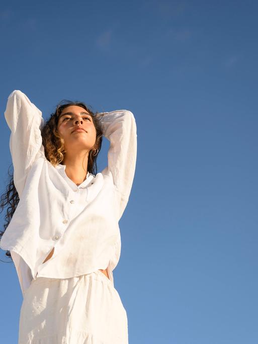 Eine Frau in weißer Kleidung vor blauem Himmel Eine Frau in weißer Kleidung vor blauem Himmel