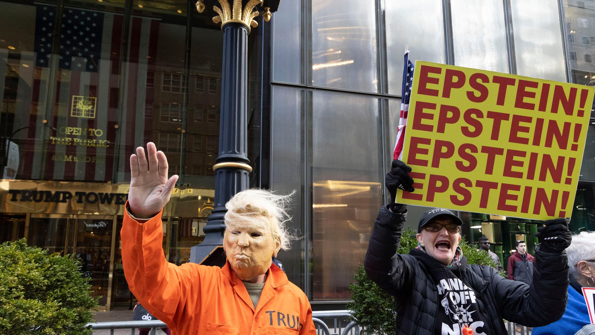 16. November 2025, New York, New York, USA: Ein Mann mit einer Trump-Maske und einem orangefarbenen Gefängnisoverall winkt Passanten auf der Fifth Avenue zu und schließt sich friedlichen Anti-Trump-Demonstranten vor dem Trump Tower an, die Schilder mit…