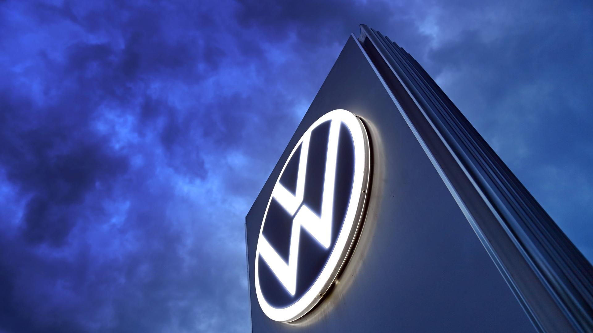 Das Volkswagen-Logo auf einer Steele vor dunklem Himmel mit vielen Wolken. Das Volkswagen-Logo auf einer Steele vor dunklem Himmel mit vielen Wolken.