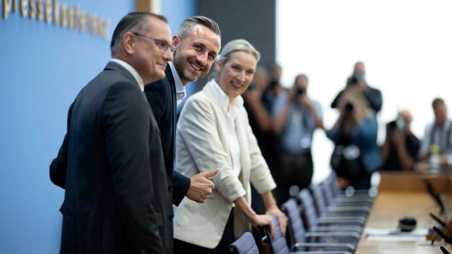 Das Bild zeigt die AfD-Vertreter von der Seite. Sie stehen vor Stühlen vor einem langen Tisch. Im Hintergrund sind der Schriftzug "Bundespressekonferenz" und mehrere Journalisten zu erahnen.