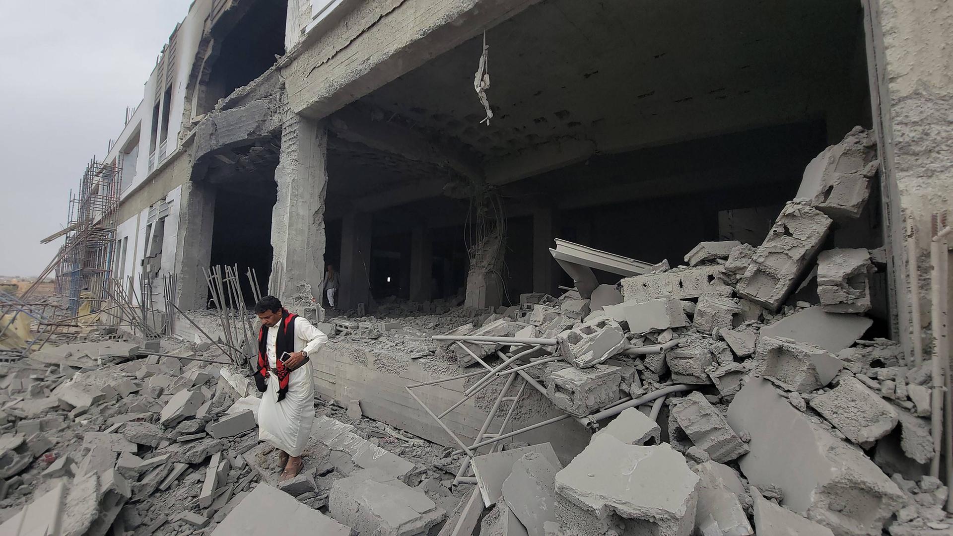 In der Stadt Sadah, im Jemen, läuft ein Mann über Schutt, hinter ihm steht ein zerstörtes Gebäude. In der Stadt Sadah, im Jemen, läuft ein Mann über Schutt, hinter ihm steht ein zerstörtes Gebäude.