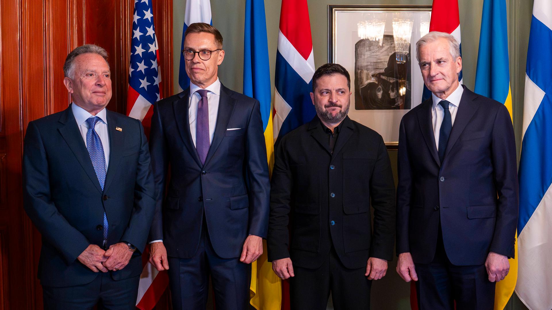 4 Politiker beim Oslo-Gipfel 2026: Witkoff (USA), Stubb (Finnland), Selenskyj (Ukraine) und Støre (Norwegen) stehen im Anzug bzw. dunkler Jacke nebeneinander vor ihren Nationalflaggen und einem gerahmten Kunstwerk für ein offizielles Gruppenfoto. 4 Politiker beim Oslo-Gipfel 2026: Witkoff (USA), Stubb (Finnland), Selenskyj (Ukraine) und Støre (Norwegen) stehen im Anzug bzw. dunkler Jacke nebeneinander vor ihren Nationalflaggen und einem gerahmten Kunstwerk für ein offizielles Gruppenfoto.