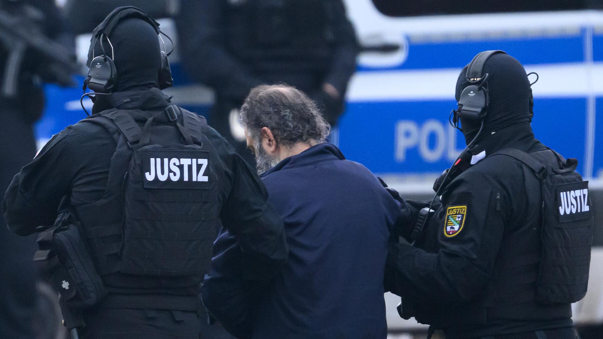 Der mutmaßliche Attentäter des Anschlags auf den Magdeburger Weihnachtsmarkt im Dezember 2024 wird von Justizpersonal zu einer Fahrzeugkolonne geführt. Der mutmaßliche Attentäter des Anschlags auf den Magdeburger Weihnachtsmarkt im Dezember 2024 wird von Justizpersonal zu einer Fahrzeugkolonne geführt.