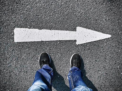 Eine Person steht vor einem Pfeil, der nach rechts zeigt Eine Person steht vor einem Pfeil, der nach rechts zeigt