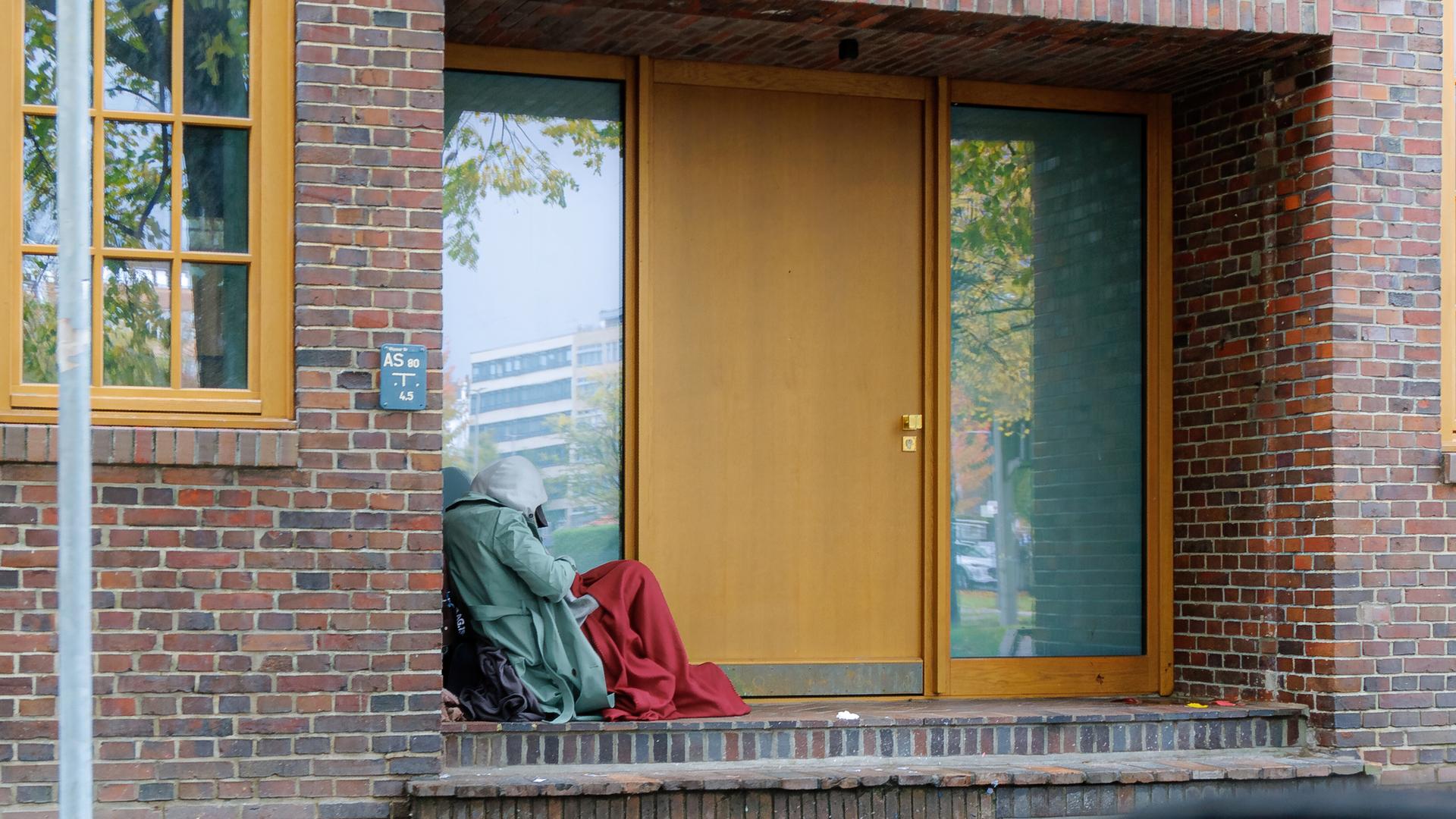 Person sitzt zusammengekauert in einem Hauseingang (Hamburg, 27.10.2025)