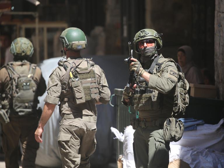 Drei israelische Soldaten patrouillieren auf einem Markt in der Altstadt von Nablus im nördlichen besetzten Westjordanland. Ein Soldat (r.) hält seine Waffe am Anschlag (23.06.2026) Drei israelische Soldaten patrouillieren auf einem Markt in der Altstadt von Nablus im nördlichen besetzten Westjordanland. Ein Soldat (r.) hält seine Waffe am Anschlag (23.06.2026)