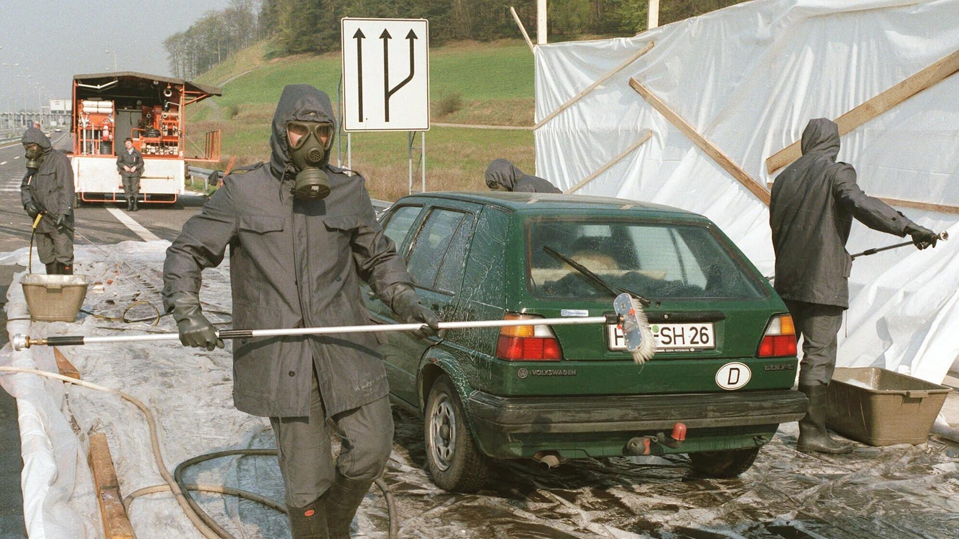 Feuerwehrleute in Schutzanzuegen reinigen 3. Mai 1986 an der innerdeutschen Grenze nahe Herleshausen westdeutsche Personenwagen, die aus Polen kommen und radioaktiv kontaminiert sind.