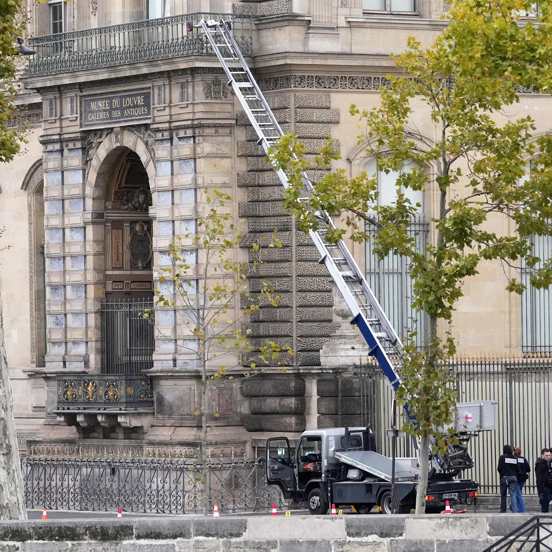 19.10.2025, Paris: Polizisten neben einem Lastenaufzug-Fahrzeug, mit dem Diebe ins Louvre eingestiegen sind.