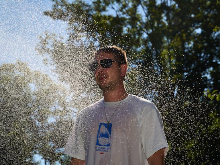 Ein Mann kühlt sich im Wassernebel ab