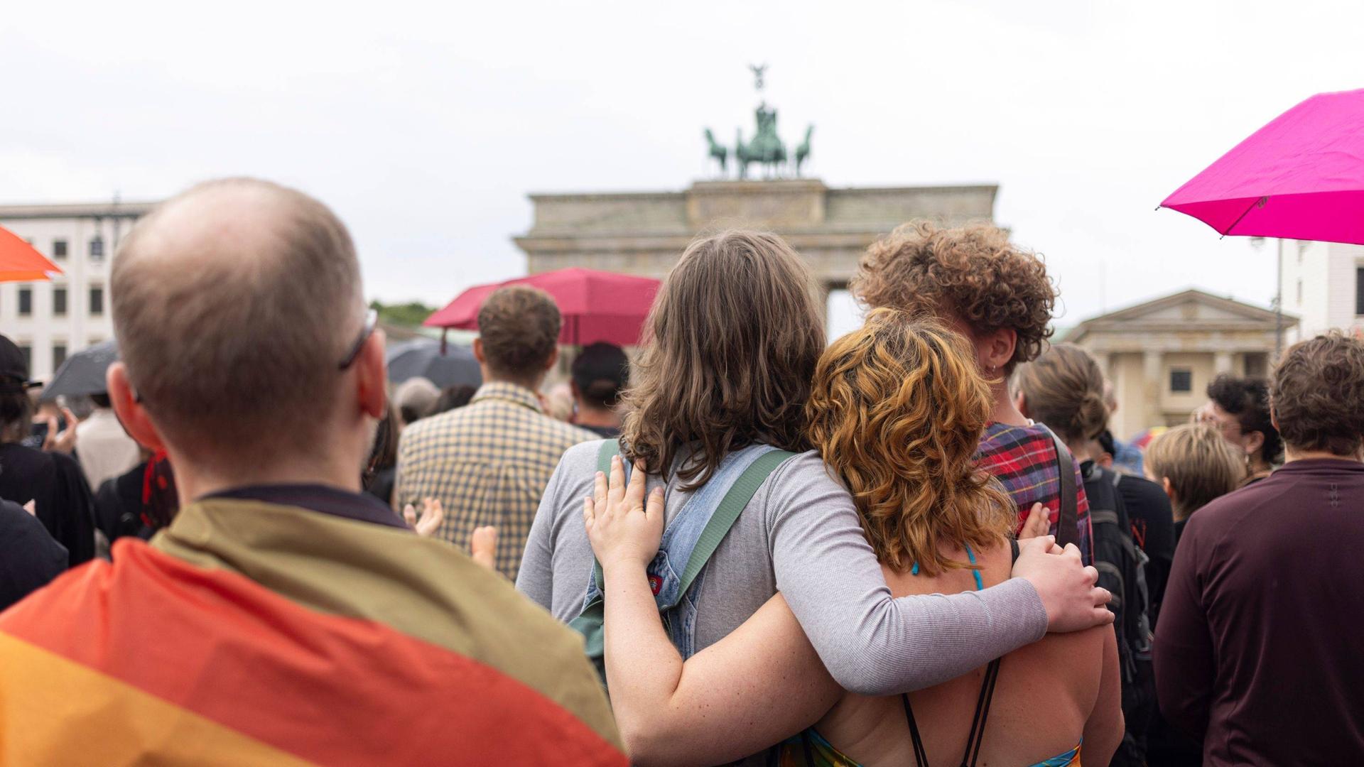 Trauernde Menschen umarmen sich vor dem Brandenburger Tor.