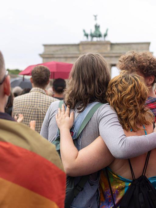 Trauernde Menschen umarmen sich vor dem Brandenburger Tor