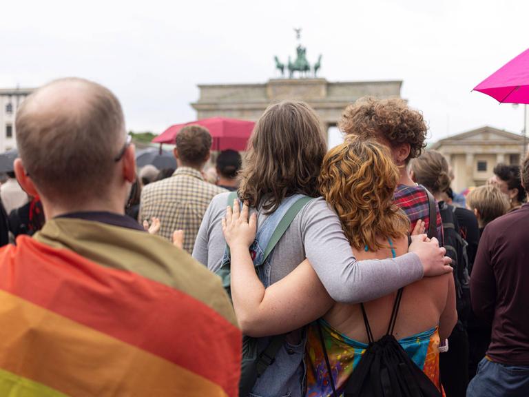 Trauernde Menschen umarmen sich vor dem Brandenburger Tor
