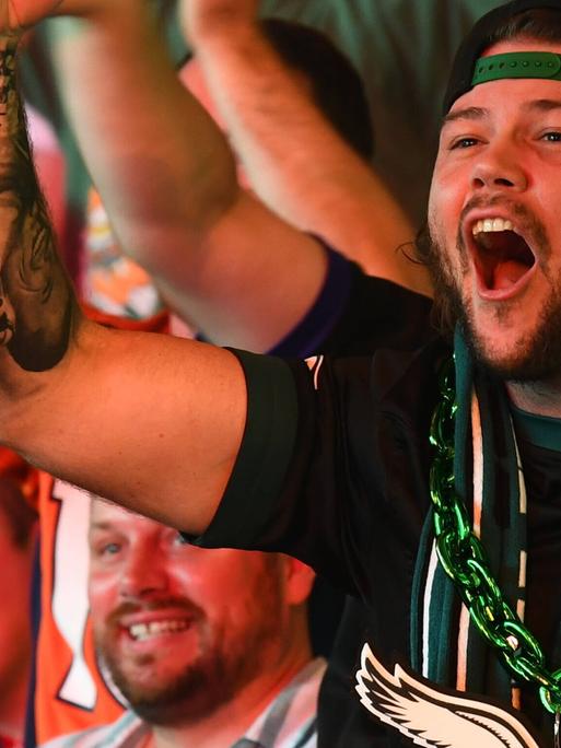 American Football Fan hebt die Faust während er bei einem Public Screening mit anderen den Super Bowl 2025 ansieht. American Football Fan hebt die Faust während er bei einem Public Screening mit anderen den Super Bowl 2025 ansieht.