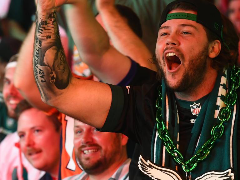 American Football Fan hebt die Faust während er bei einem Public Screening mit anderen den Super Bowl 2025 ansieht. American Football Fan hebt die Faust während er bei einem Public Screening mit anderen den Super Bowl 2025 ansieht.