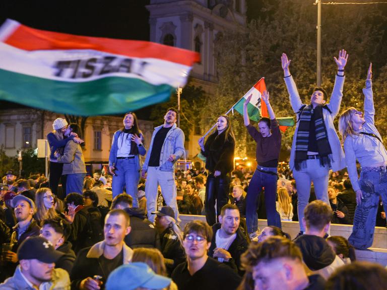 Junge Leute stehen auf einer Mauer und schwenken Ungarn-Flaggen nach dem Wahlsieg von  Péter Magyar (Budapest 13.04.2026)