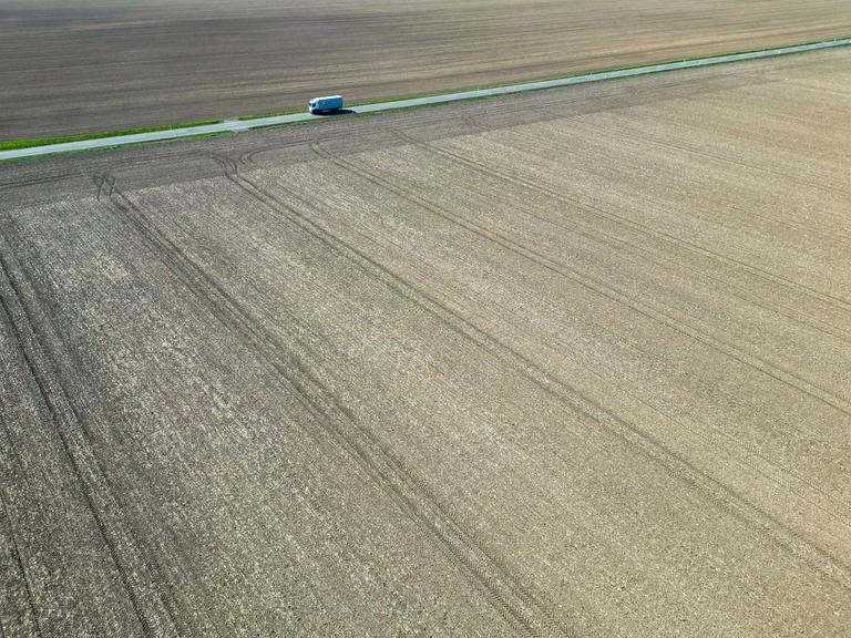 Ein Lkw fährt zwischen trockenen Feldern über eine Landstraße in Nordsachsen. Auch in den kommenden Tagen sagen die Meteorologen keine Niederschläge voraus. (Luftaufnahme mit Drohne)