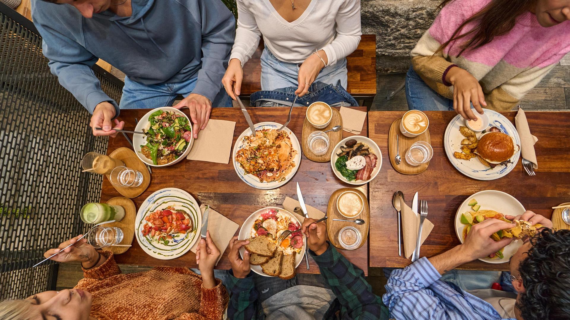 Mehrere Leute essen gemeinsam im Restaurant, das Bild ist von oben fotografiert. 