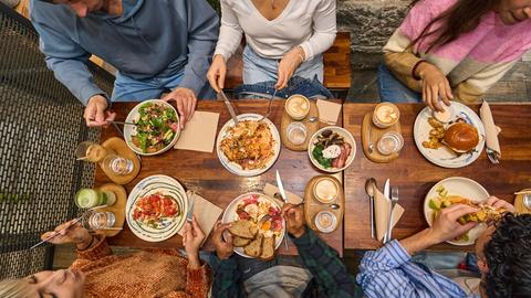 Mehrere Leute essen gemeinsam im Restaurant, das Bild ist von oben fotografiert. 
