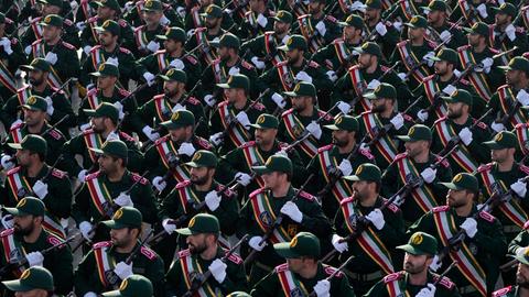 Soldaten der iranischen Revolutionsgarden marschieren durch Teheran bei einer Parade. Die Soldaten blicken alle nach rechts, sie tragen eine Waffe.