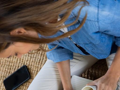 Journaling - eine junge Frau schreibt in ein leeres Notizbuch.