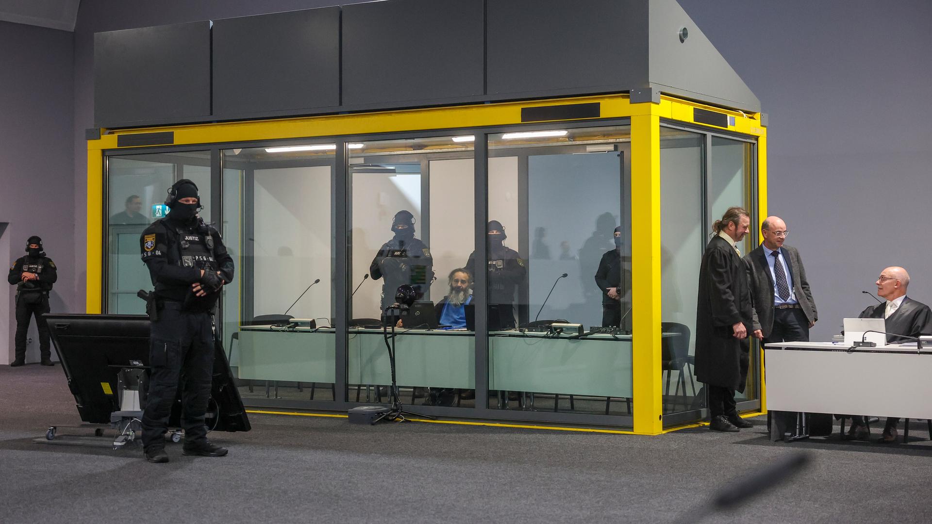 Der Angeklagte von Magdeburg in einem Glaskasten, um ihn Polizisten. Der Angeklagte von Magdeburg in einem Glaskasten, um ihn Polizisten.