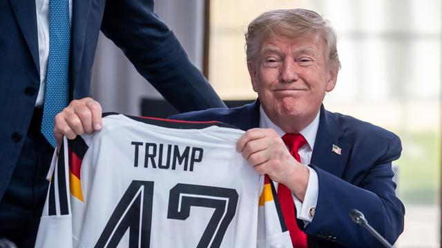 US-Präsident Donald Trump hält ein DFB-Fußball-Trikot mit dem Namen Trump und der Rückennummer 47, das er vom deutschen Kanzler Friedrich Merz bei einem Treffen der G7 bekommen hat 