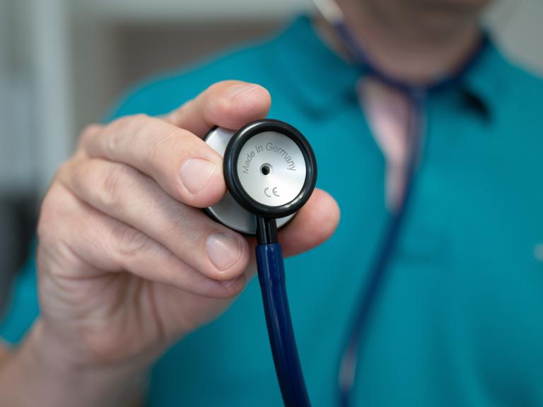Person hält Stethoskop vor sich Person hält Stethoskop vor sich