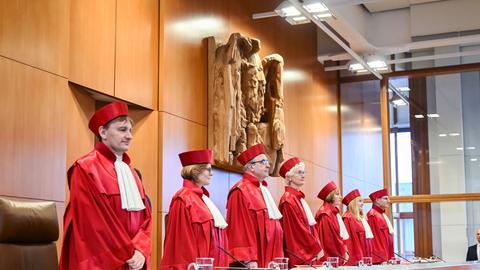Die Richterinnen und Richter des Bundesverfassungsgerichts stehen zu Beginn einer Verhandlung. Sie tragen rote Roben.