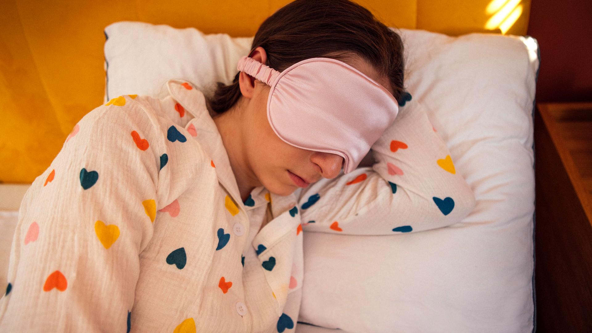 Eine Frau liegt mit einer Schlafmaske im Bett Eine Frau liegt mit einer Schlafmaske im Bett