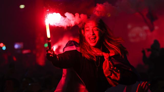 Eine junge Frau hält bei einer Wahlsiegesfeier von Anhängern der oppositionellen Studentenliste vor dem Gebäude der Nationalversammlung der Republik Serbien in Belgrad lachend ein rot brennendes Bengalo in der Hand.