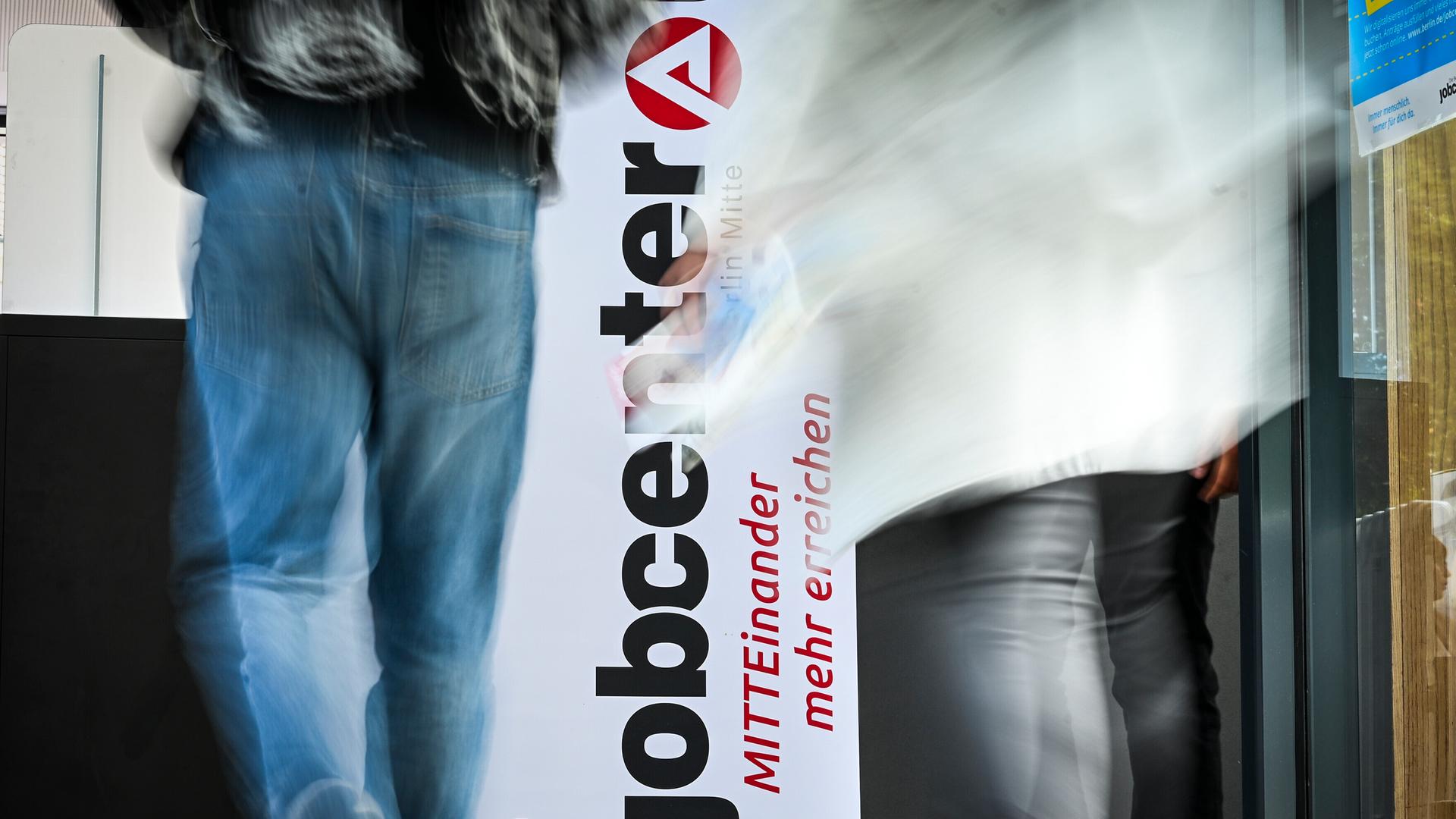 Personen gehen am Logo vom Jobcenter Berlin-Mitte bei der Jobmesse vorbei