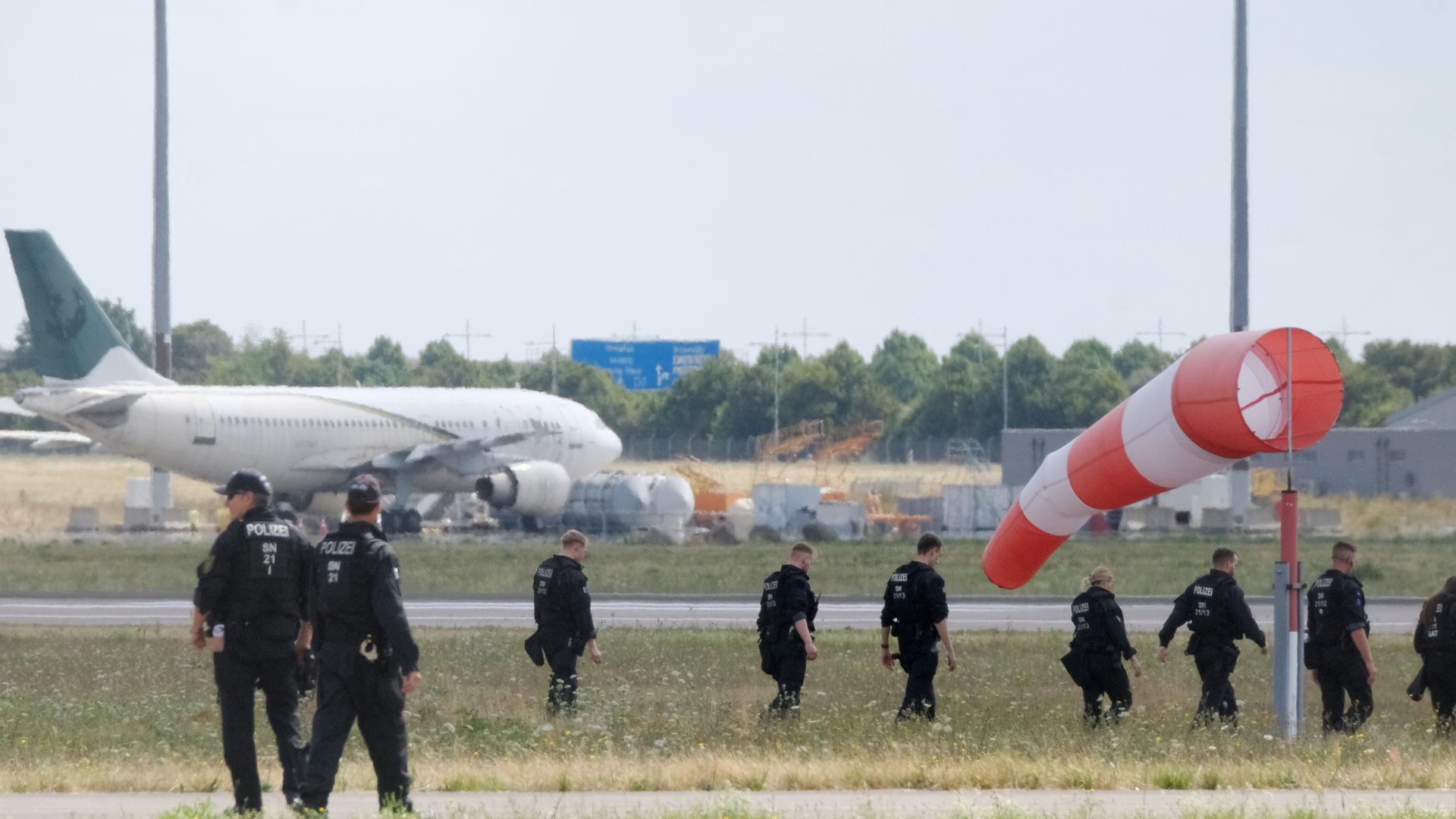 Polizisten gehen über eine Wiese auf dem Gelände des Flughafen Leipzig/Halle (7.08.2026) Polizisten gehen über eine Wiese auf dem Gelände des Flughafen Leipzig/Halle (7.08.2026)