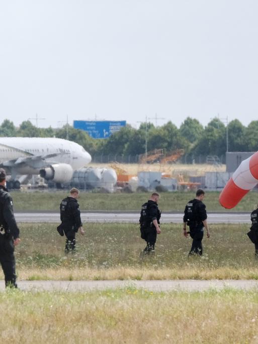 Polizisten gehen über eine Wiese auf dem Gelände des Flughafen Leipzig/Halle (7.08.2026) Polizisten gehen über eine Wiese auf dem Gelände des Flughafen Leipzig/Halle (7.08.2026)