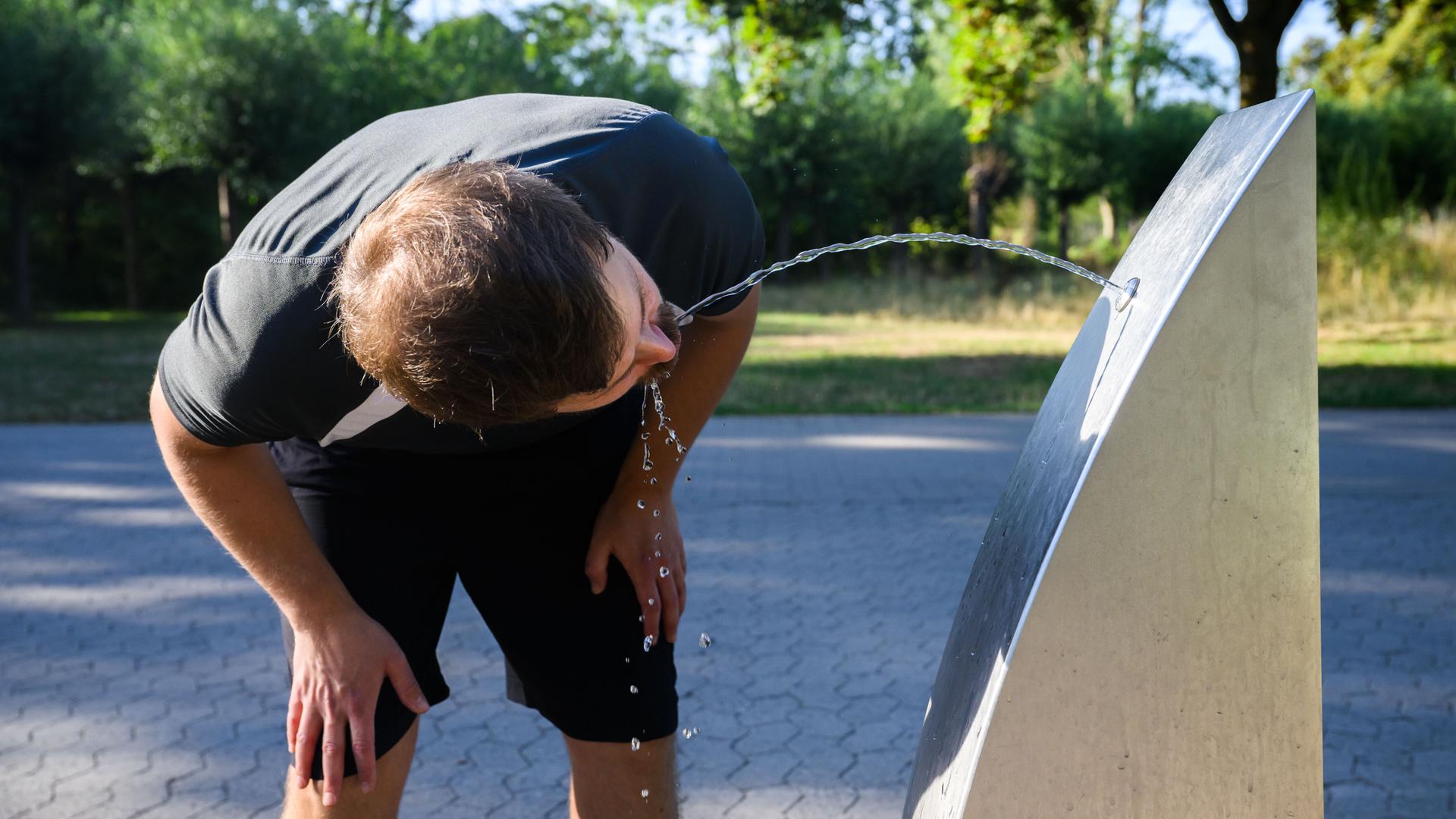 Ein Sportler trinkt Wasser an einem öffentlichen Trinkwasserspender der Stadt Hannover.
