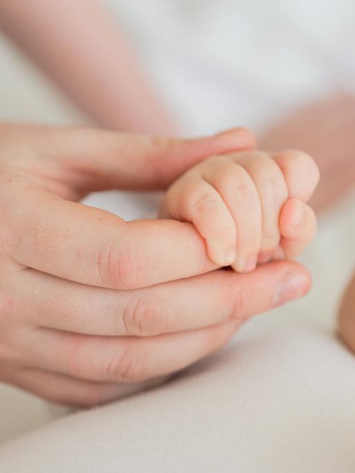 Eine Mutter hält die Hand ihres Babys
