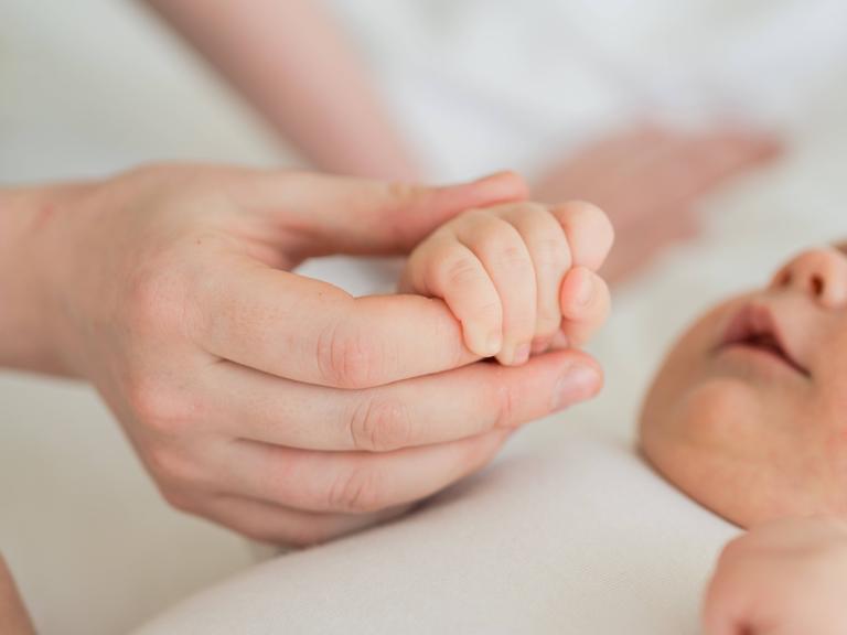 Eine Mutter hält die Hand ihres Babys