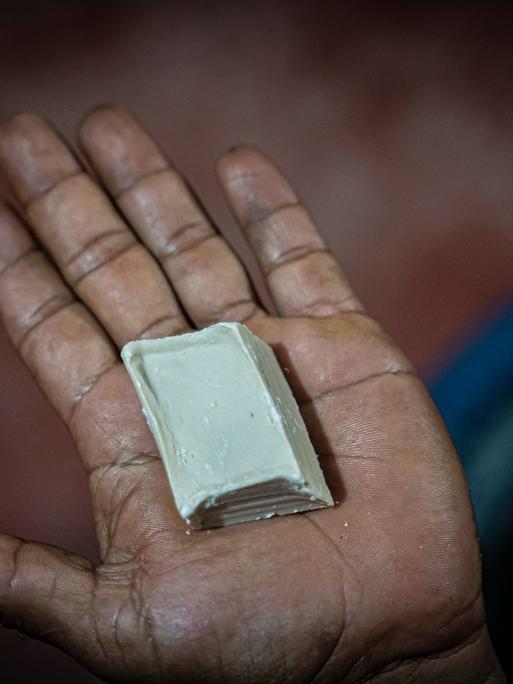 Ein Mann zeigt ein Stück Kokapaste am Rande einer Koka-Plantage, wo Kokablätter zu Paste verarbeitet werden.