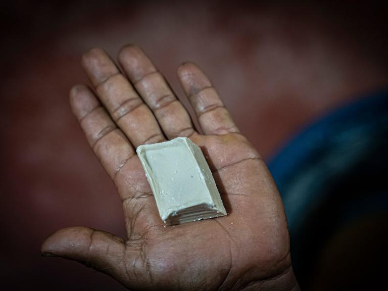 Ein Mann zeigt ein Stück Kokapaste am Rande einer Koka-Plantage, wo Kokablätter zu Paste verarbeitet werden.